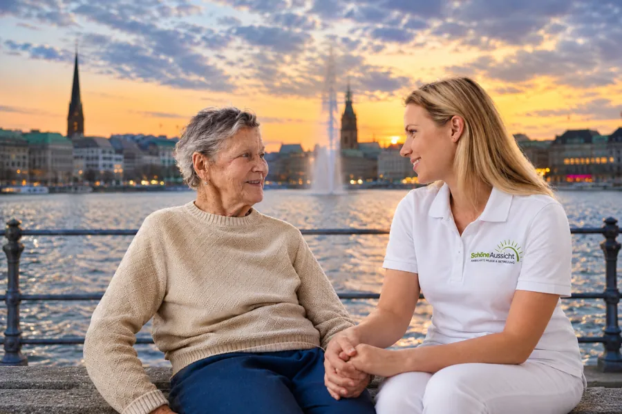Pflegekraft von Schöne Aussicht mit einer Seniorin an der Alster, im Hintergrund die Hamburger Innenstadt